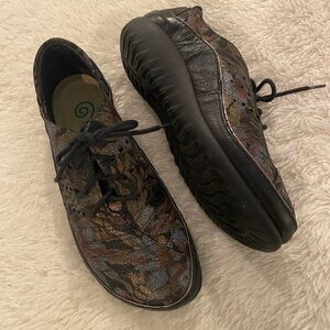 NAOT Kumara flat shoe in a multi-colored, metallic, and floral leather finish.